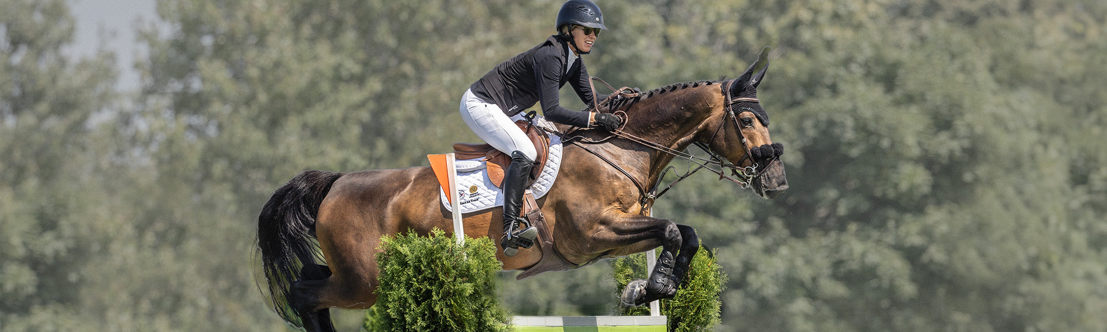 Canadian Olympic show jumper Amy Millar wearing a black Seaver SAFEFIT airbag vest while mounted on a horse in an arena.