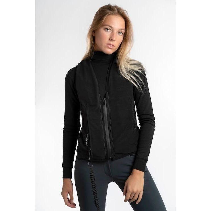 Young female rider modeling a black low-profile airbag vest over a long-sleeve base layer and dark riding tights